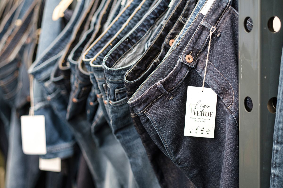 Viele Jeans hängen an einem Messestand.