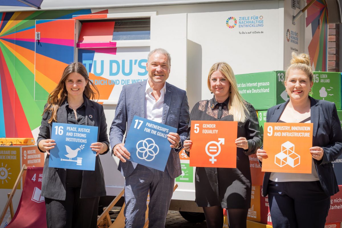 Vier Personen mit Schildern der 17 SDGs in der Hand.