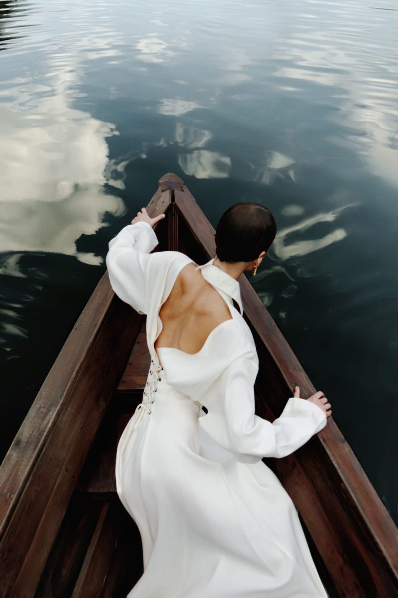 Model in Ruderboot trägt ein weißes Kleid.