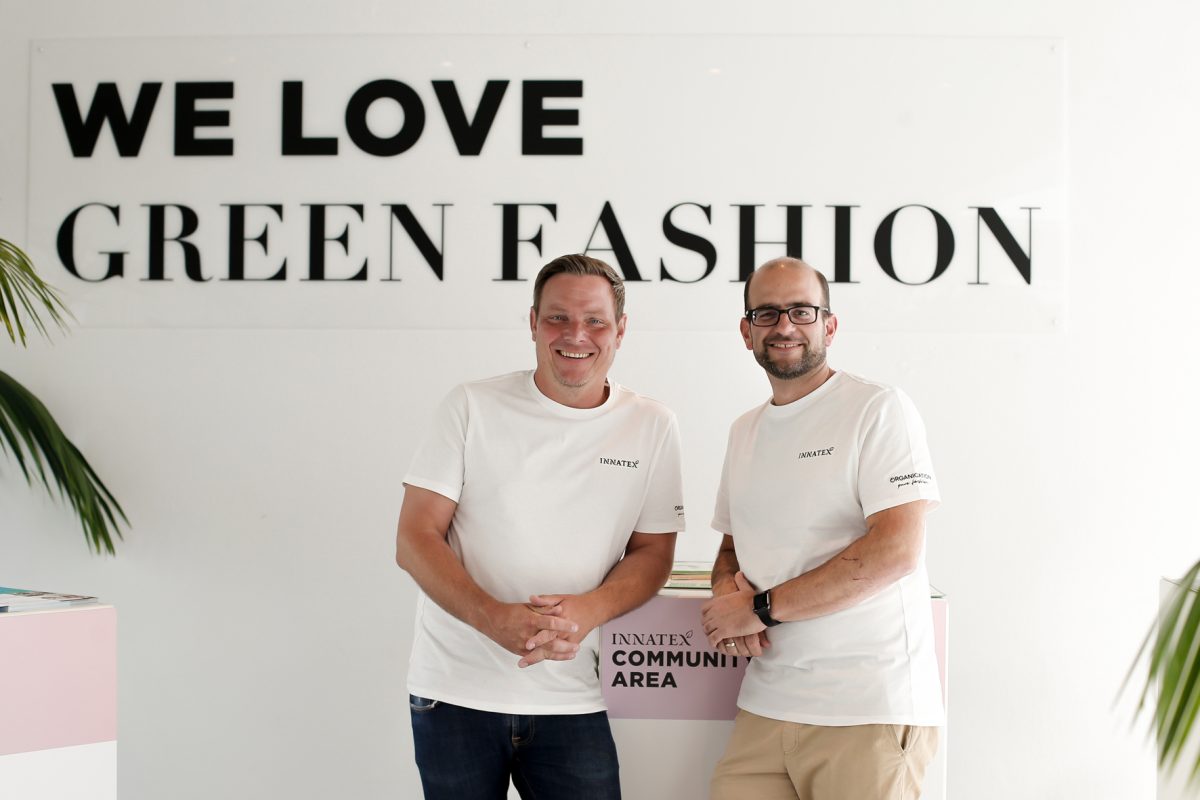 Jens Frey und Alexander Hitzel stehen vor einer Wand auf der 'We love Green Fashion' steht.