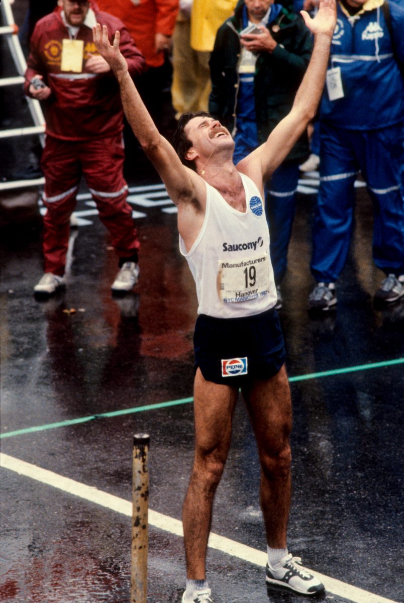 Marathonläufer reißt die Arme hoch, nachdem er durchs Ziel ist.